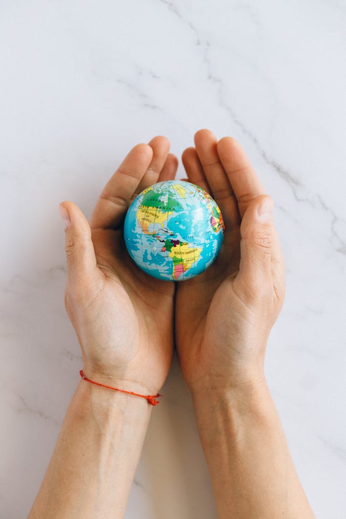 Close-up of hands gently holding a small globe representing global unity and care.