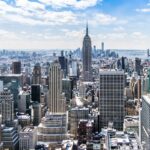 A stunning aerial view of New York City's skyline featuring the iconic Empire State Building under a bright blue sky.
